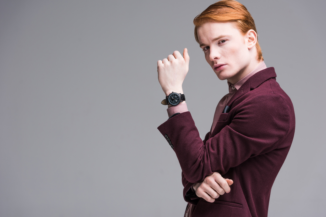 Young male fashion model with wristwach isolated on grey